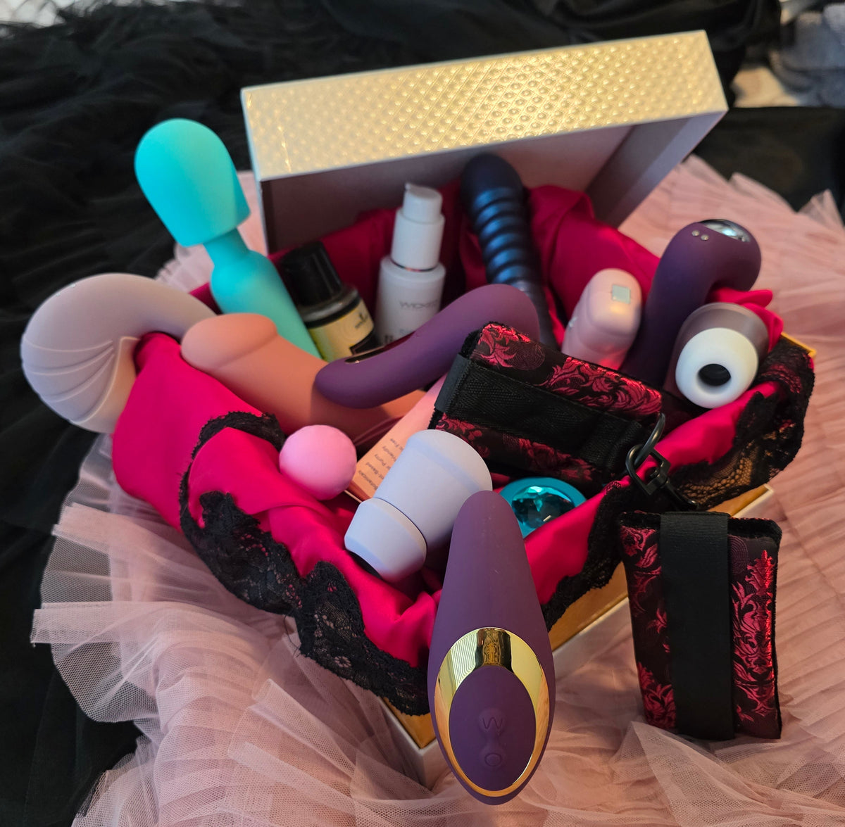 Collection of various toys in a decorative box on a textured surface.